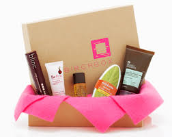 A brown birchbox with pink lettering and several types of makeup surroudning the box.